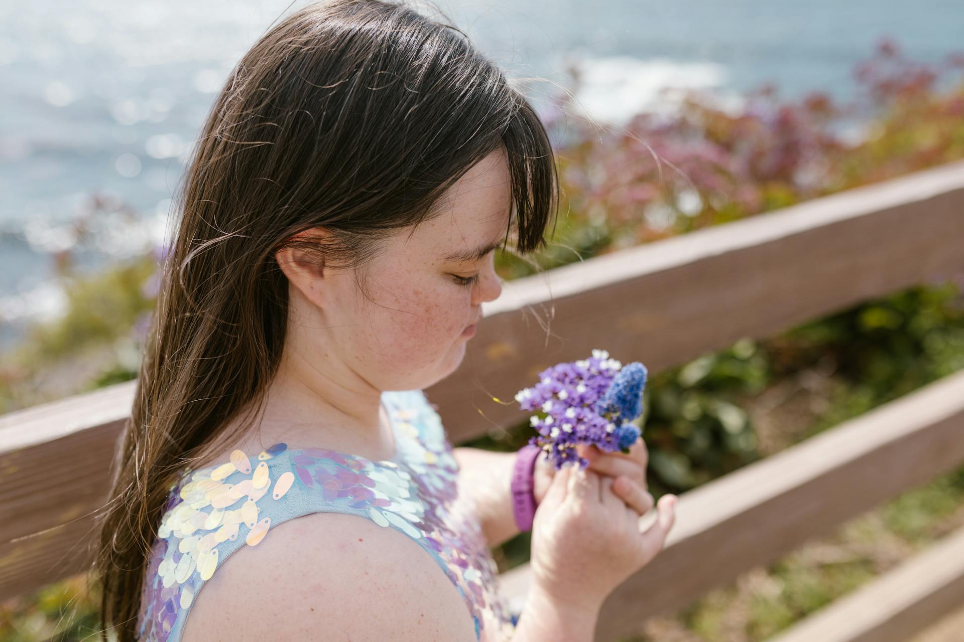 Portrait of a young girl with Down syndrome holding flowers outdoors.