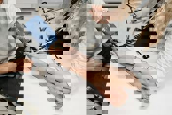 A person in a lab coat checks another's blood pressure with a blue cuff and stethoscope.