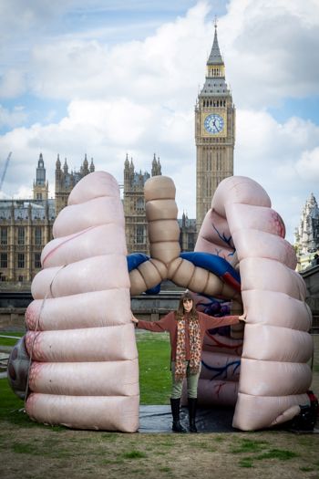 A woman standing in front of a large pair of inflated lungs 