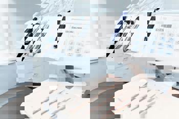 Close-up of a dental workstation featuring dental tools, a digital control panel, and a tray. 